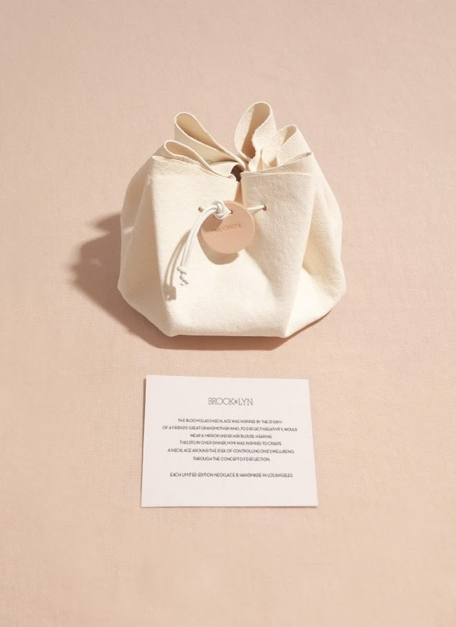 a small white bag sitting on top of a table next to a paper card and envelope