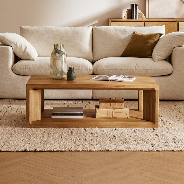 a living room with a couch, coffee table and books on the floor in front of it