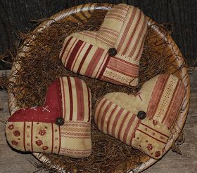 three red and white striped heart shaped pillows in a wicker basket on top of hay