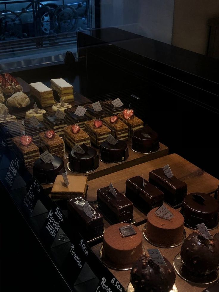 a display case filled with lots of different types of cakes and desserts on top of wooden boards