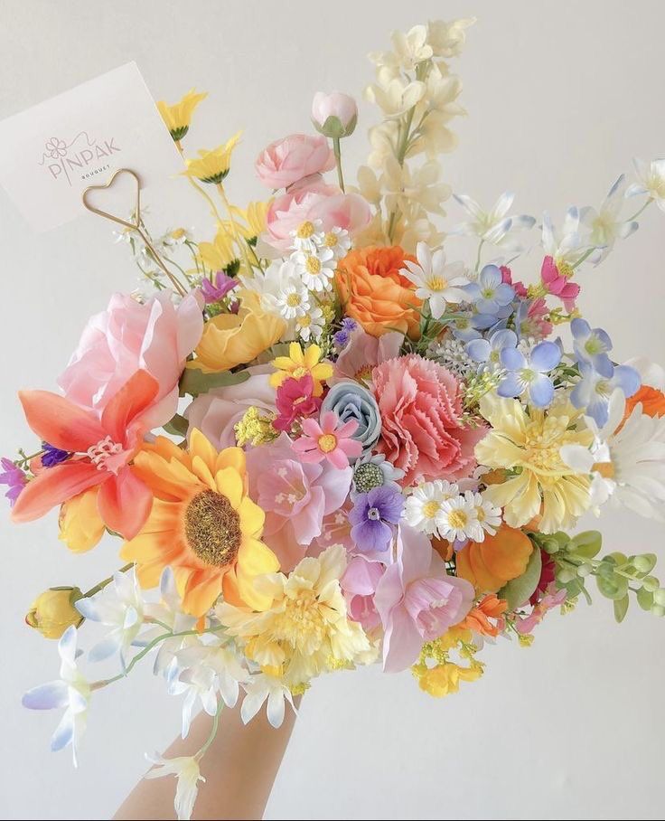 a woman holding a bouquet of flowers in her hand with a note attached to it