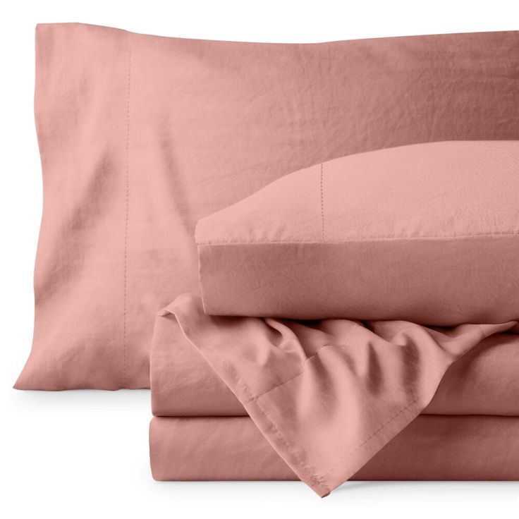 two sheets and one pillow on top of each other with pink sheets in the background