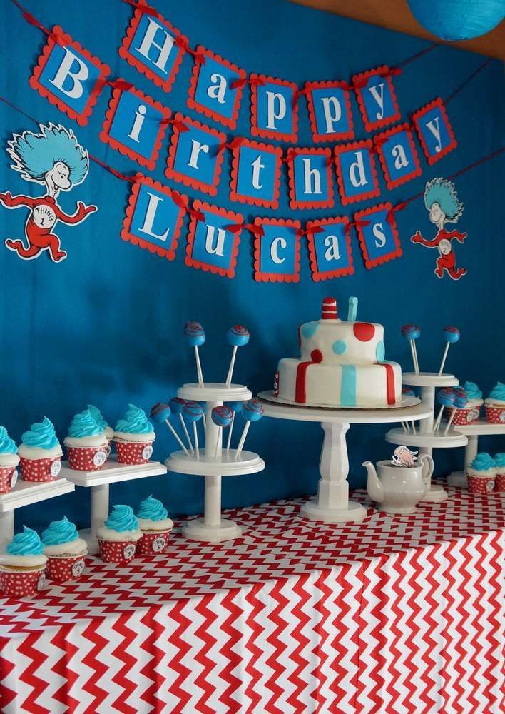 a birthday cake and cupcakes on a table in front of a blue wall