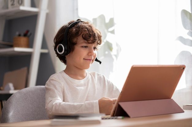 a young boy sitting at a desk with a laptop and headphones on his ears