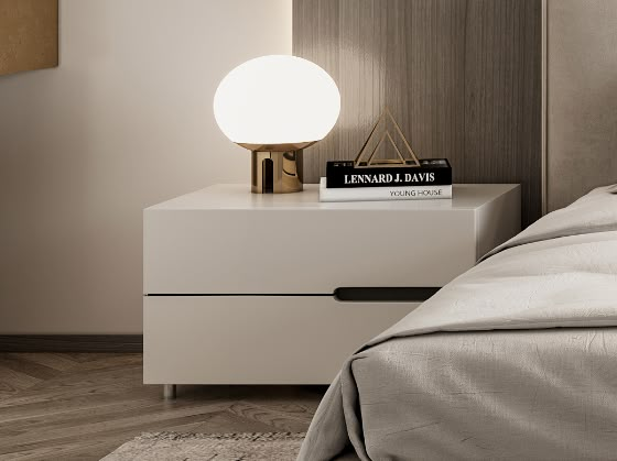 a nightstand with a lamp on top of it next to a bed