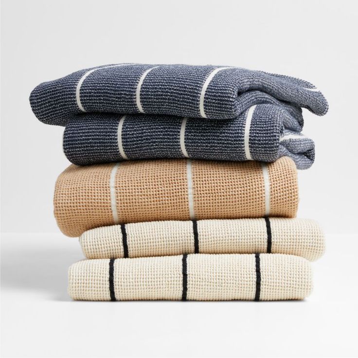 three folded towels stacked on top of each other in different colors and patterns, with one folded up to the side