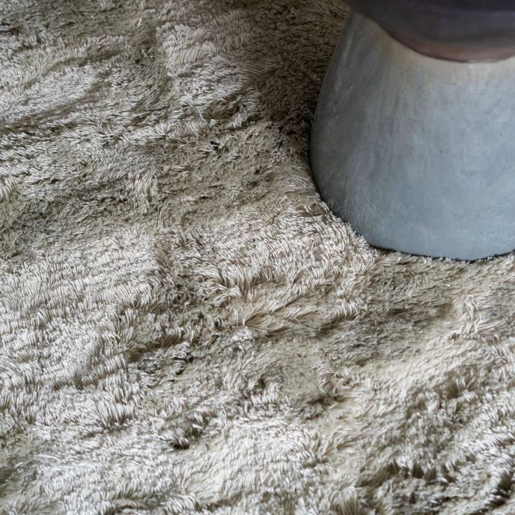 a close up view of a table on a shaggy carpeted surface with a vase in the middle