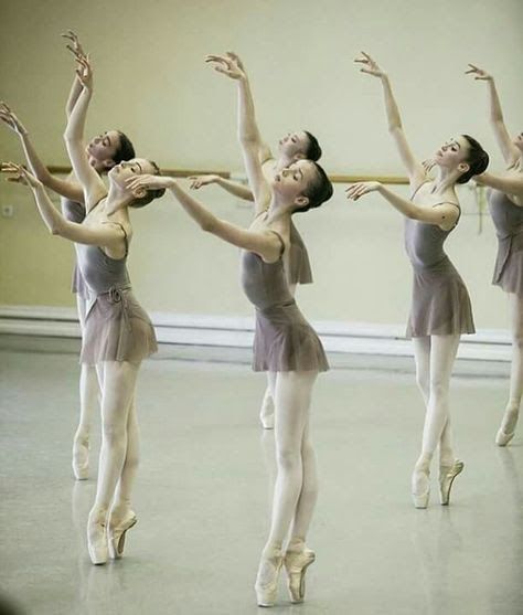 four ballerinas are performing in an empty room with their arms stretched out to the side