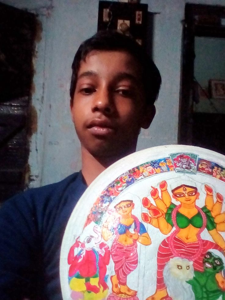 a young man holding up a painted plate