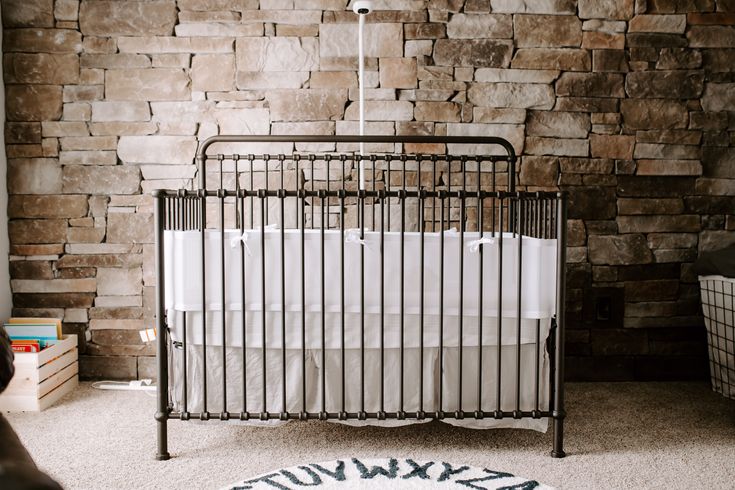 a baby crib in front of a stone wall