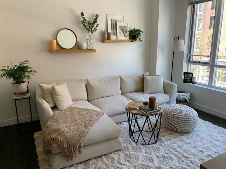 a living room with a white couch and two round tables in front of a large window