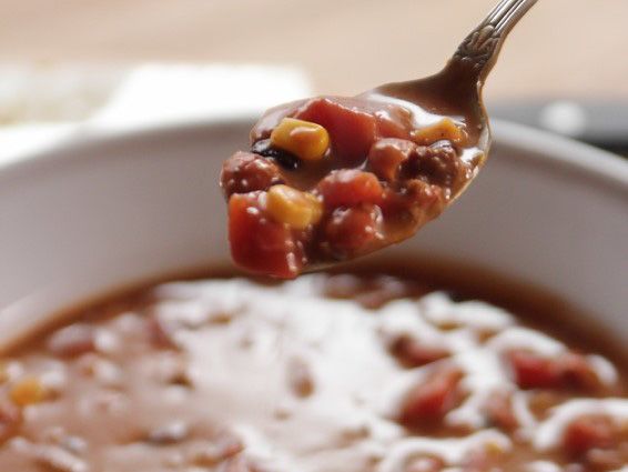 a spoon full of chili and cheese soup