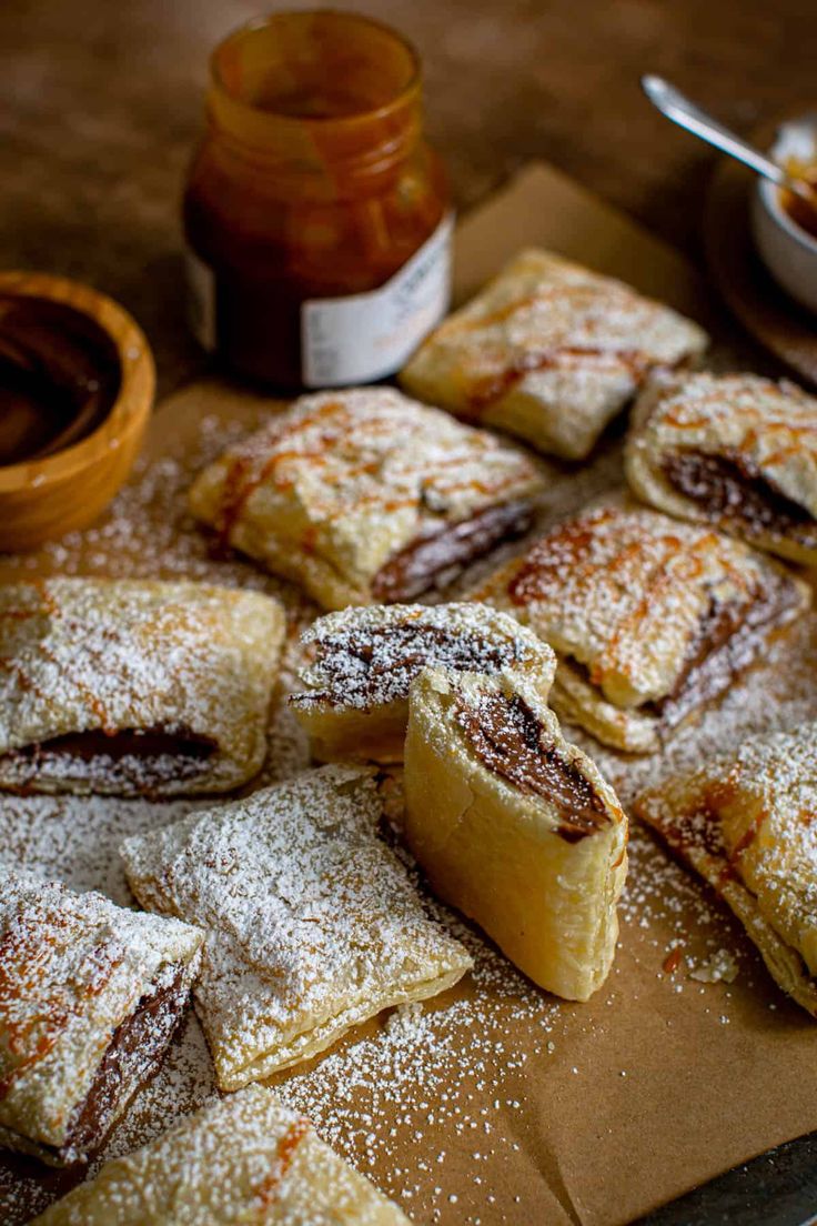 powdered sugar covered pastries on a cutting board next to some condiments