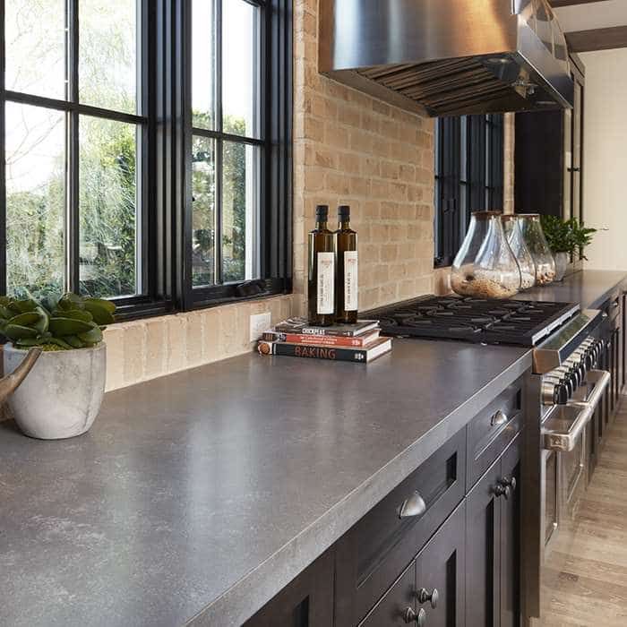 a kitchen with a stove top oven sitting next to a window filled with wine bottles