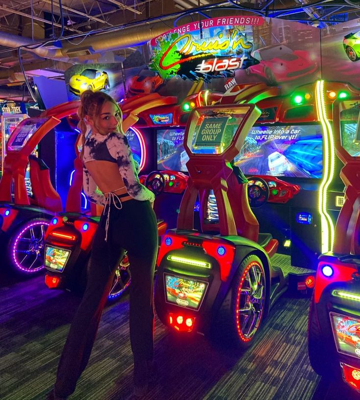 a woman is standing in front of several arcade machines with neon lights on the sides