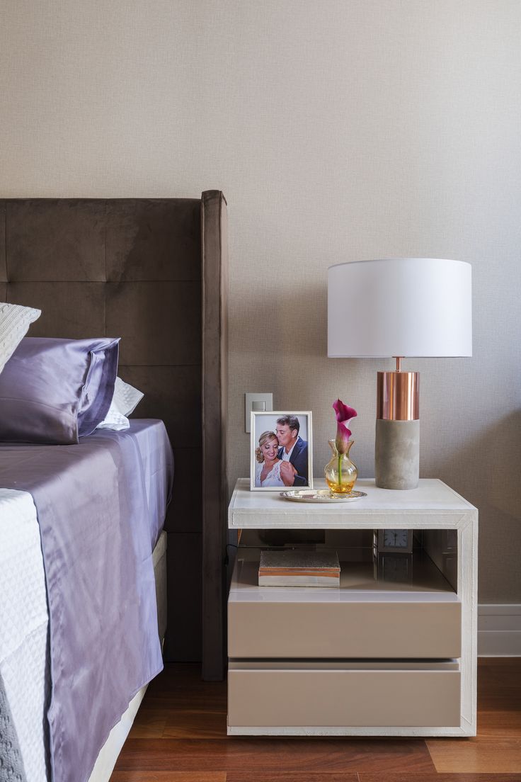 a bedroom with a bed, nightstand and pictures on the night stand next to it