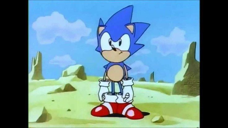 sonic the hedgehog is standing in front of some rocks and sand with his arms outstretched