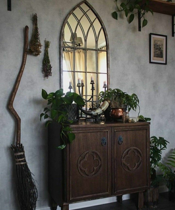 a room with a mirror, potted plants and a wooden cabinet