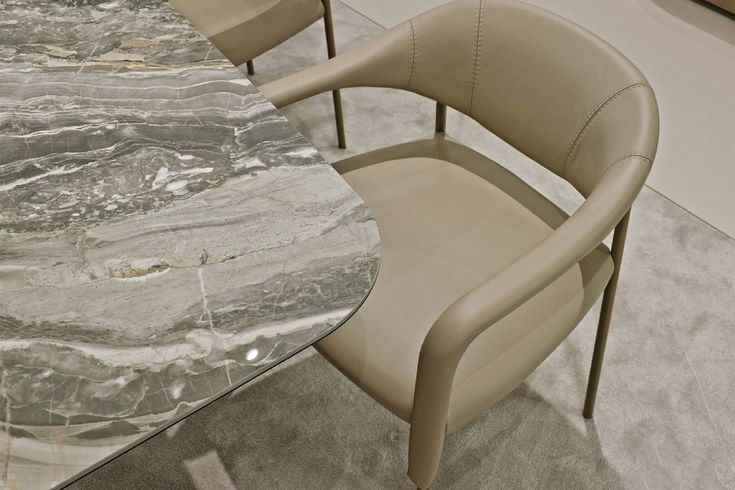 two chairs and a table in a room with marbled flooring on the walls