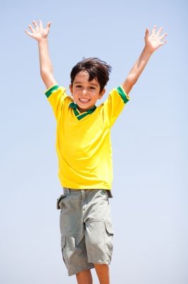 a young boy jumping in the air with his hands up