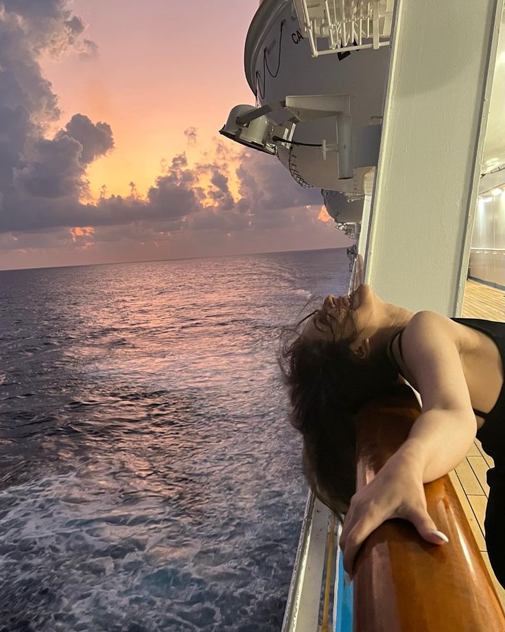 a woman is sleeping on the deck of a boat at sunset or sunrise, with her eyes closed