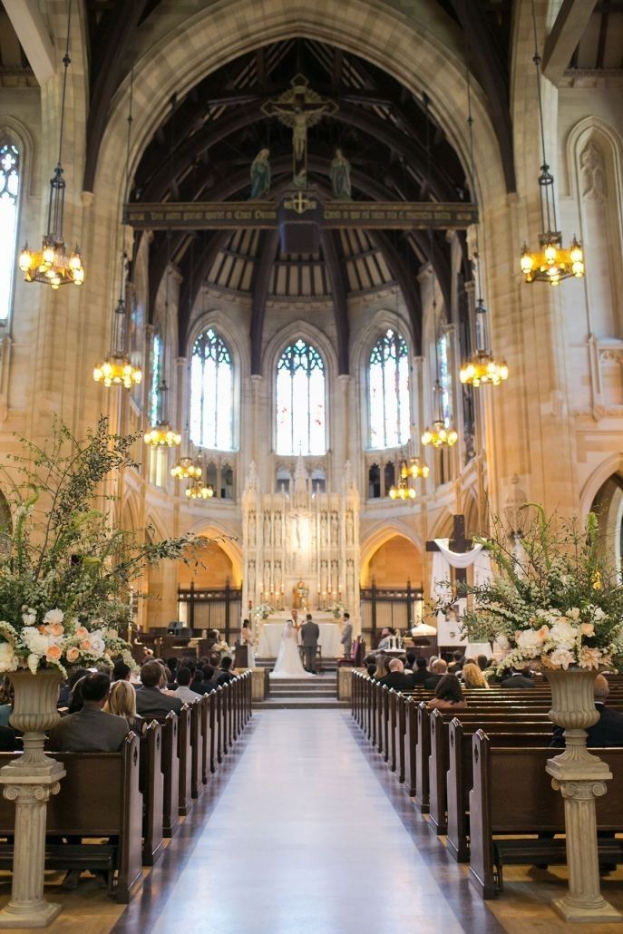 the inside of a church with pews and flower arrangements on each side of the aisle