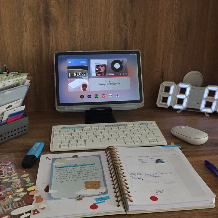 an open notebook sitting on top of a desk next to a computer monitor and keyboard