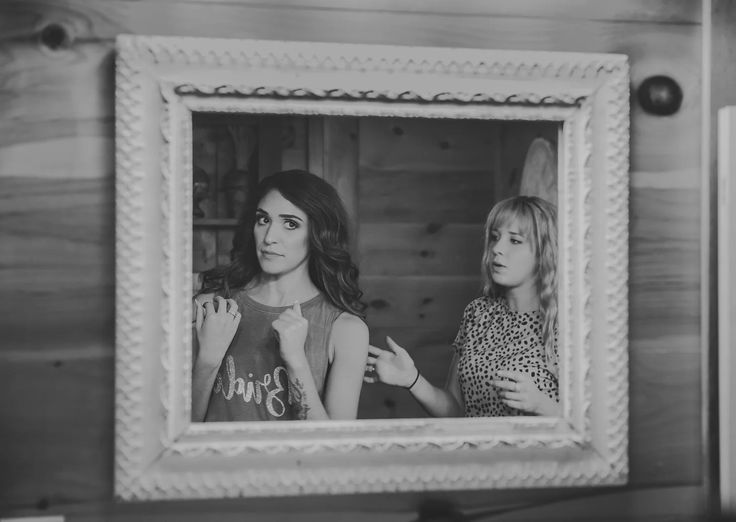 two women standing in front of a mirror