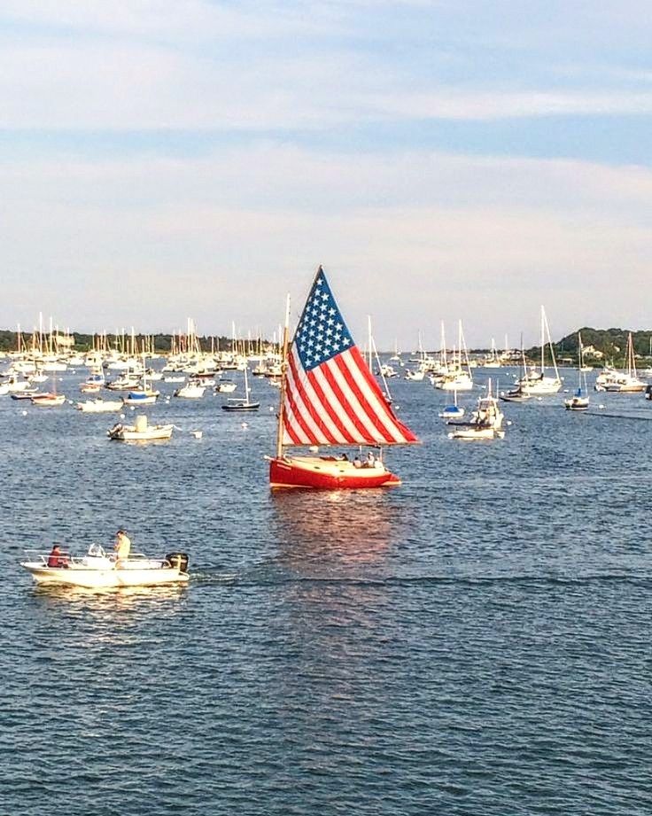 several small boats floating in the water with an american flag on one side and another boat behind them