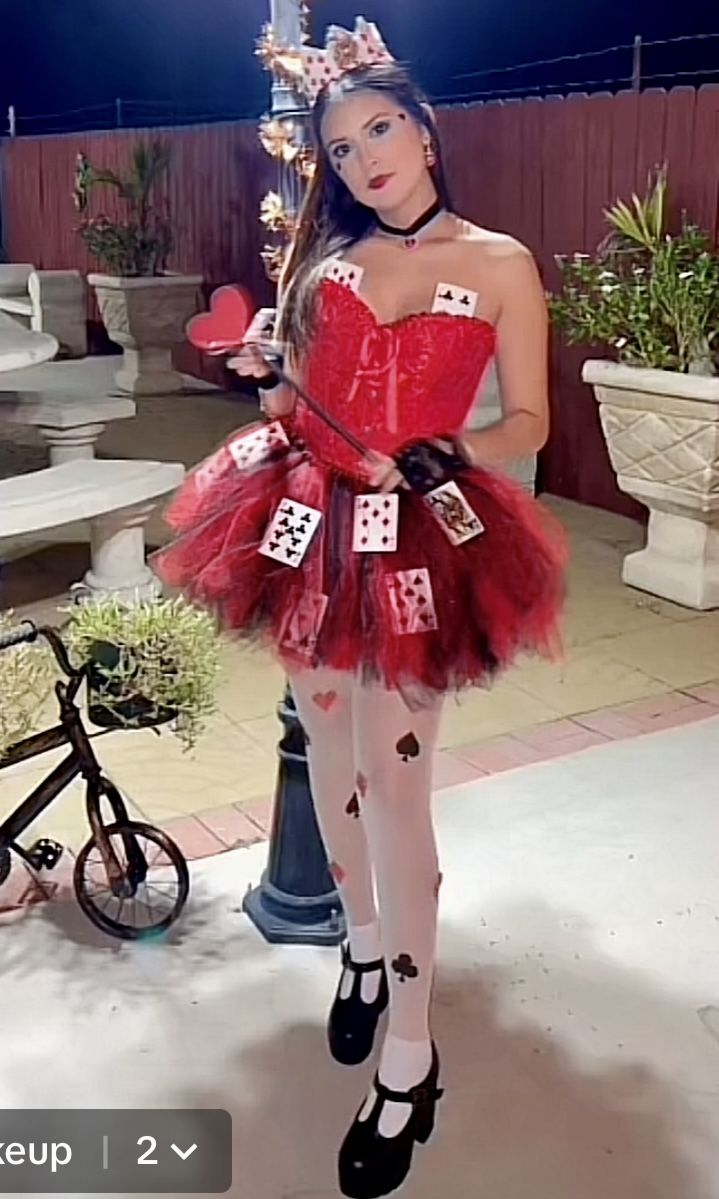 a woman in a red dress holding onto a string with dices on it and wearing a tiara