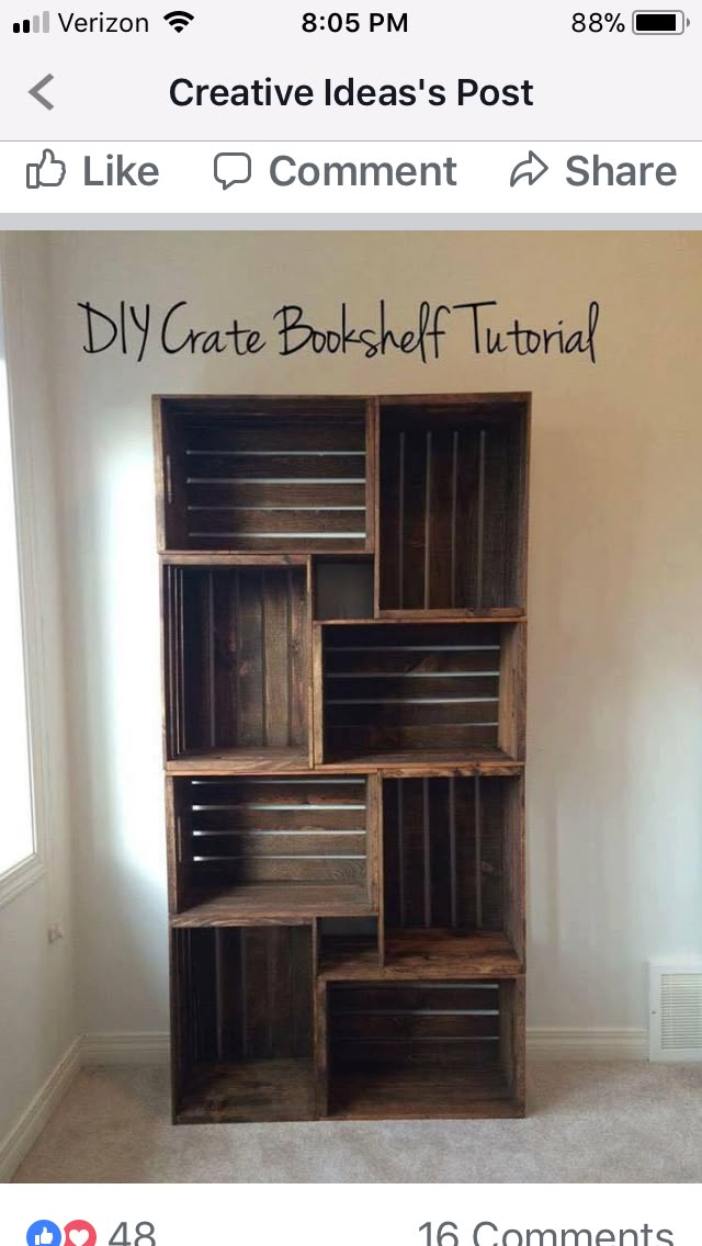 a bookcase made out of wooden crates sitting on top of a carpeted floor