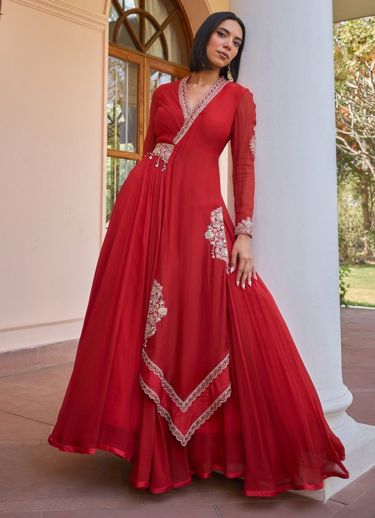 Elevate your ethnic wardrobe with the exquisite Red Layered and Embroidered Anarkali Gown, a perfect blend of tradition and contemporary style. Crafted from luxurious georgette and organza, the red gown showcases a timeless layered design with an elegant drape. Intricately adorned with tilla work, dori, pearls, handmade tassels, brass sequins, and bead embroidery, this outfit is a masterpiece of craftsmanship. The ensemble is complemented by an attached embroidered belt and a soft net dupatta, a Red Floor-length Anarkali Set With Pallu, Red Lehenga With Sheer Dupatta And Long Sleeves, Elegant Red Anarkali Set With Cutdana, Red Georgette Kurta With Traditional Drape, Red Organza Dress For Navratri, Red Anarkali Set For Reception And Eid, Red Gown For Reception And Navratri, Red Semi-stitched Anarkali Set For Reception, Traditional Draped Georgette Gown With Cutdana