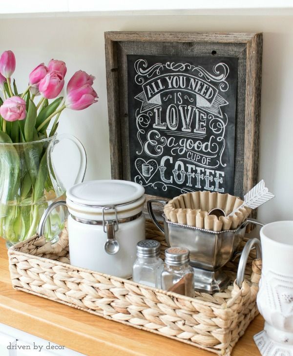 a wooden shelf topped with jars filled with pink tulips next to a chalkboard