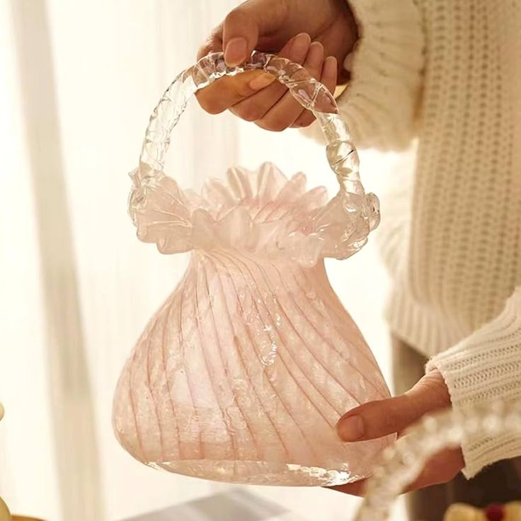 a person holding a pink glass vase in their hand