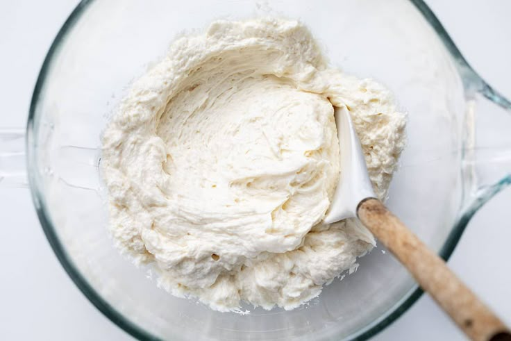 a bowl filled with whipped cream next to a wooden spoon