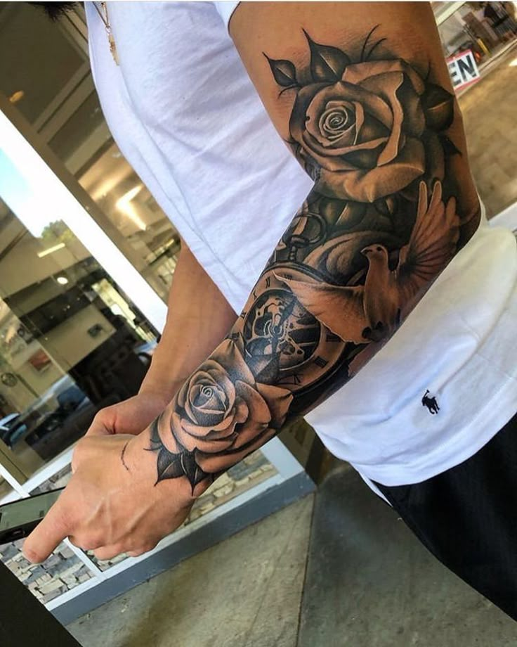 a man with a rose tattoo on his arm holding the hand of another mans wrist