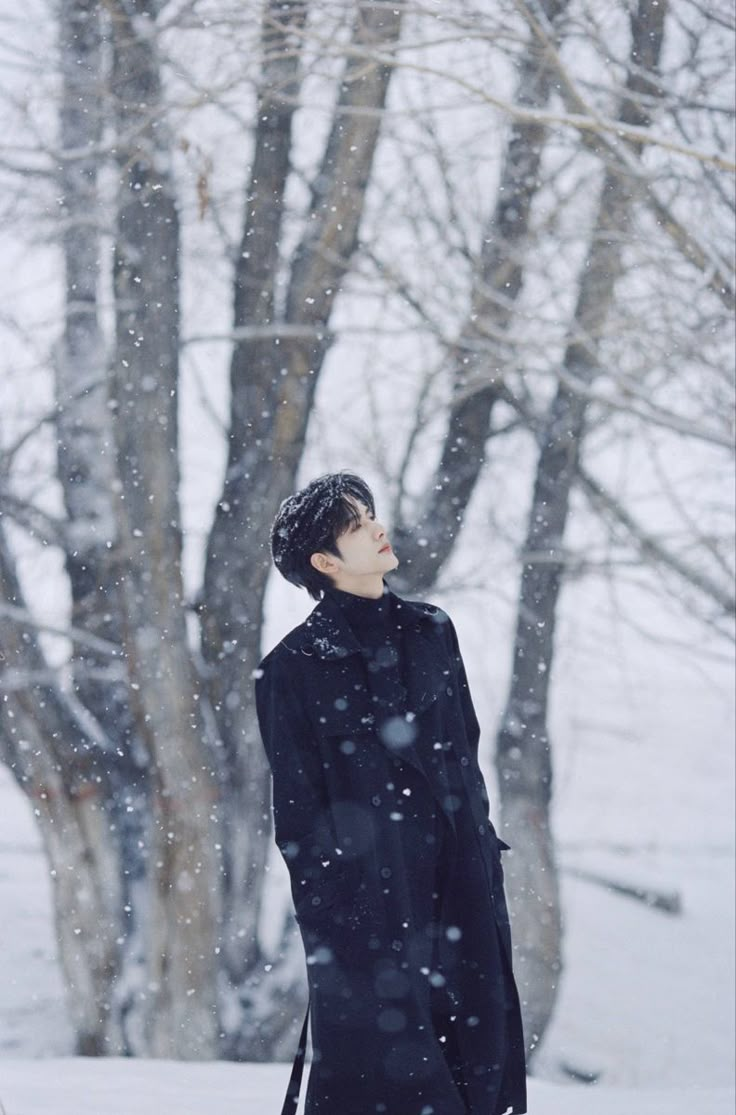 a young man standing in the snow looking up