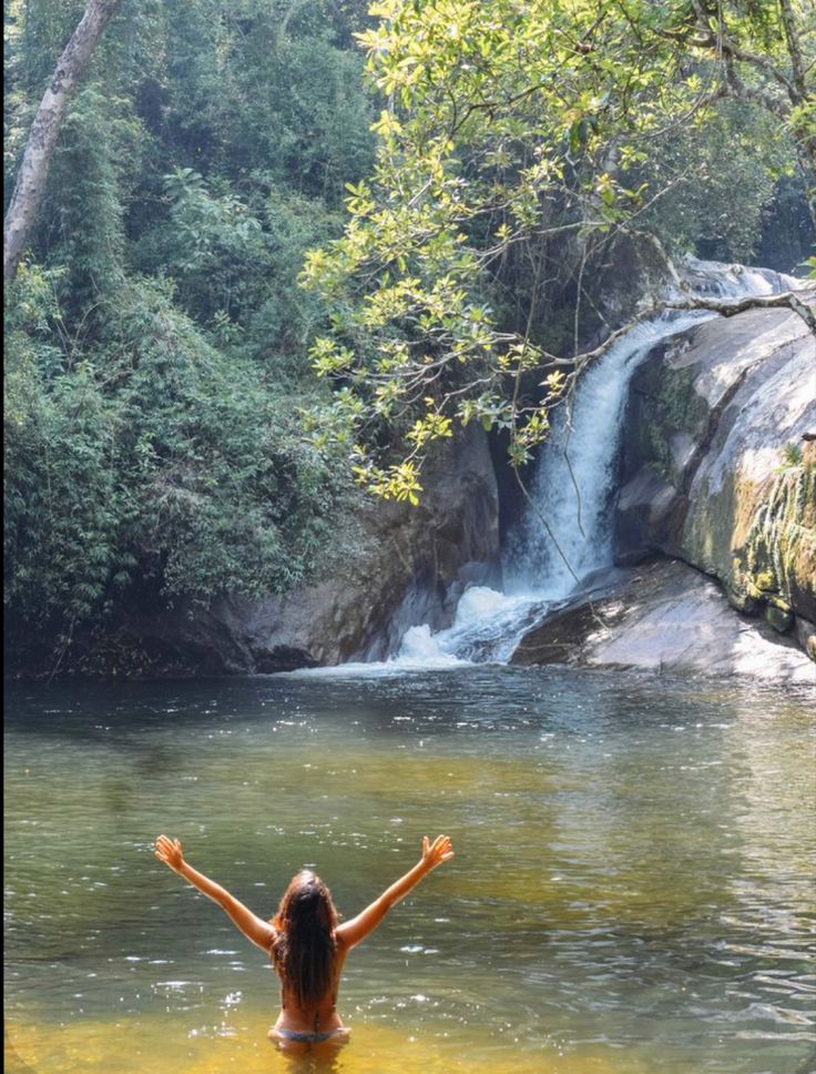 a woman standing in the middle of a body of water with her arms spread out