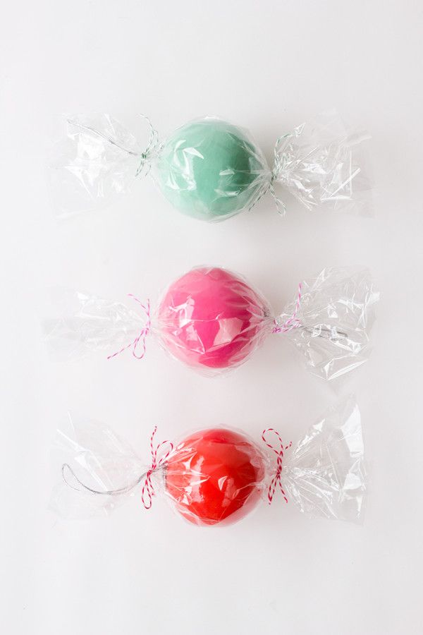 three different colored candies wrapped in cellophane on a white surface, one is red and the other is green