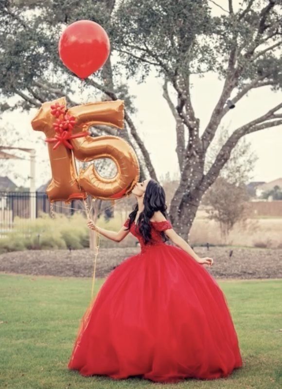 a woman in a red dress holding balloons with the number five on it and an animal balloon