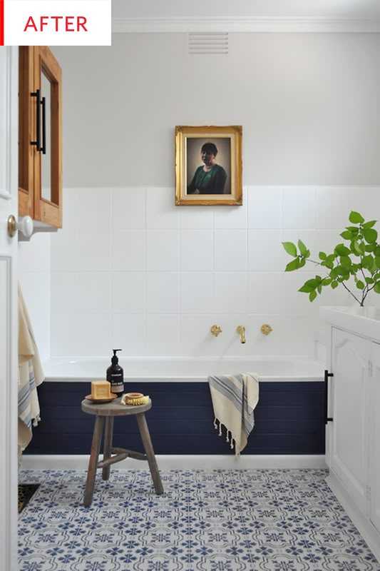 a blue and white tiled bathroom with a painting on the wall above the bathtub