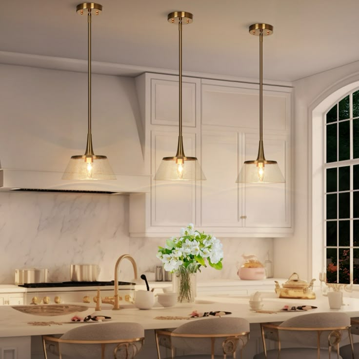 a kitchen filled with lots of counter top space and lights hanging from the ceiling above it