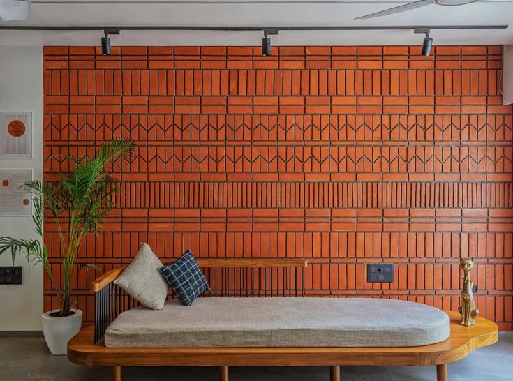 a bed sitting in front of a brick wall next to a potted green plant