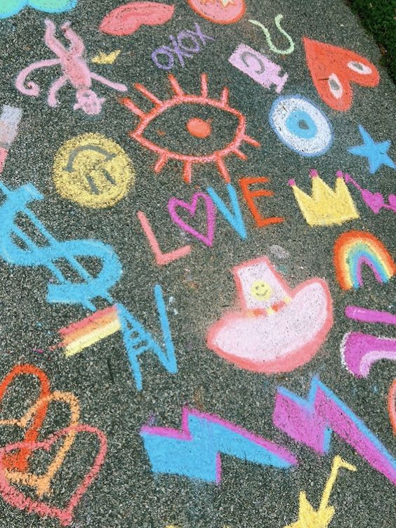 the sidewalk is covered in chalk and has many different colored letters on it, including one that says love