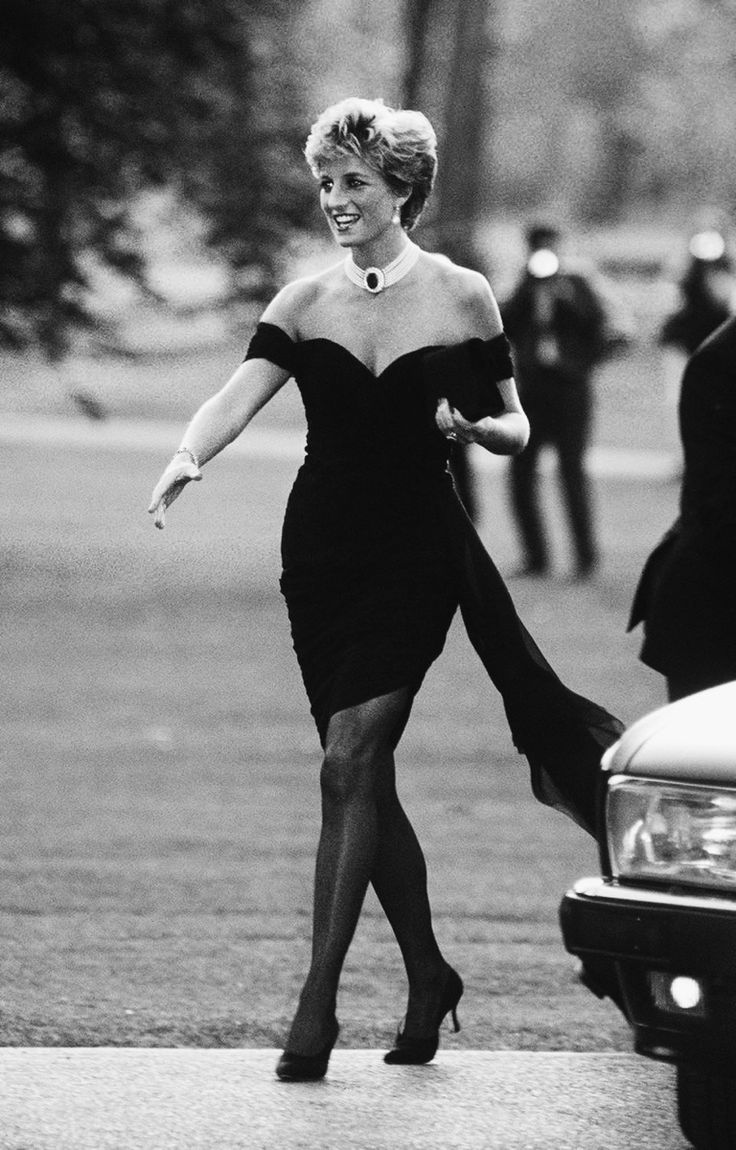 a woman in a black dress is walking down the street with her legs spread out