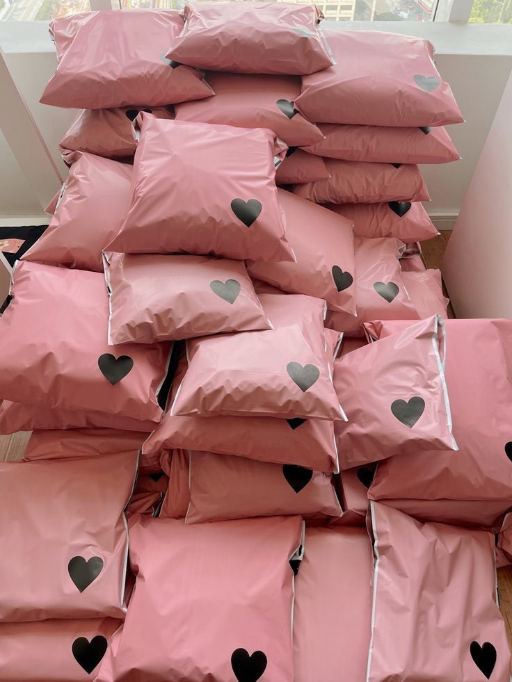 a pile of pink pillows with black hearts on them