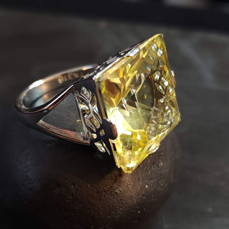 Stainless Steel ring with a split ring band and large 18mm pale yellow cubic zirconia (CZ) stone. ◄ FEATURES ► * Silver ring size 7 * Metal stamp says TK316 (steel) * Statement ring. High quality. Lots of sparkle. * The Topaz/Citrine CZ is 18mm. * The front of the ring is 10 tall. * The ring band is 2.5mm wide at the back. For size reference: * a U.S. penny is 19.05mm diameter.  * a U.S. nickel is 21.21mm diameter.  * a U.S. quarter is 24.26mm diameter.  ◄ HOW TO CARE FOR CZ JEWELRY ► 1. Keep it clean. Clean your CZ jewelry regularly to maintain its luster and shine. Use a soft-bristled brush or a soft cloth to gently wipe away dirt, dust and grime. 2. Store it safely. When not in use, store your CZ jewelry in a safe place, such as a jewelry box or a cloth pouch. Keep it away from other je Formal Yellow Topaz Ring With Diamond Accents, Yellow Topaz Ring With Diamond Center Stone, Yellow Round Cut Diamond Ring Gift, Yellow Topaz Diamond Ring With Center Stone, Yellow Topaz Ring With Diamond Accents, Anniversary Yellow Topaz Ring With Diamond Accents, Hallmarked Yellow Topaz Promise Ring, Yellow Hallmarked Topaz Promise Ring, Citrine Diamond Ring With Diamond Accents