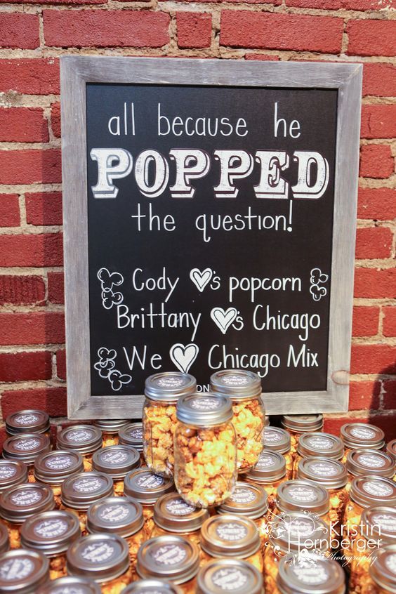 a table filled with lots of food next to a chalkboard that says popped the question