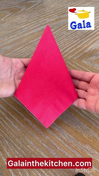 a person is holding a pink piece of paper in their hand on a wooden table