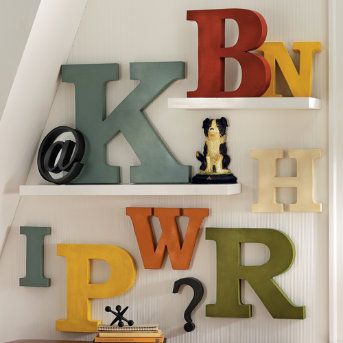 the letters are painted on the wall above the bookshelf and below the stairs